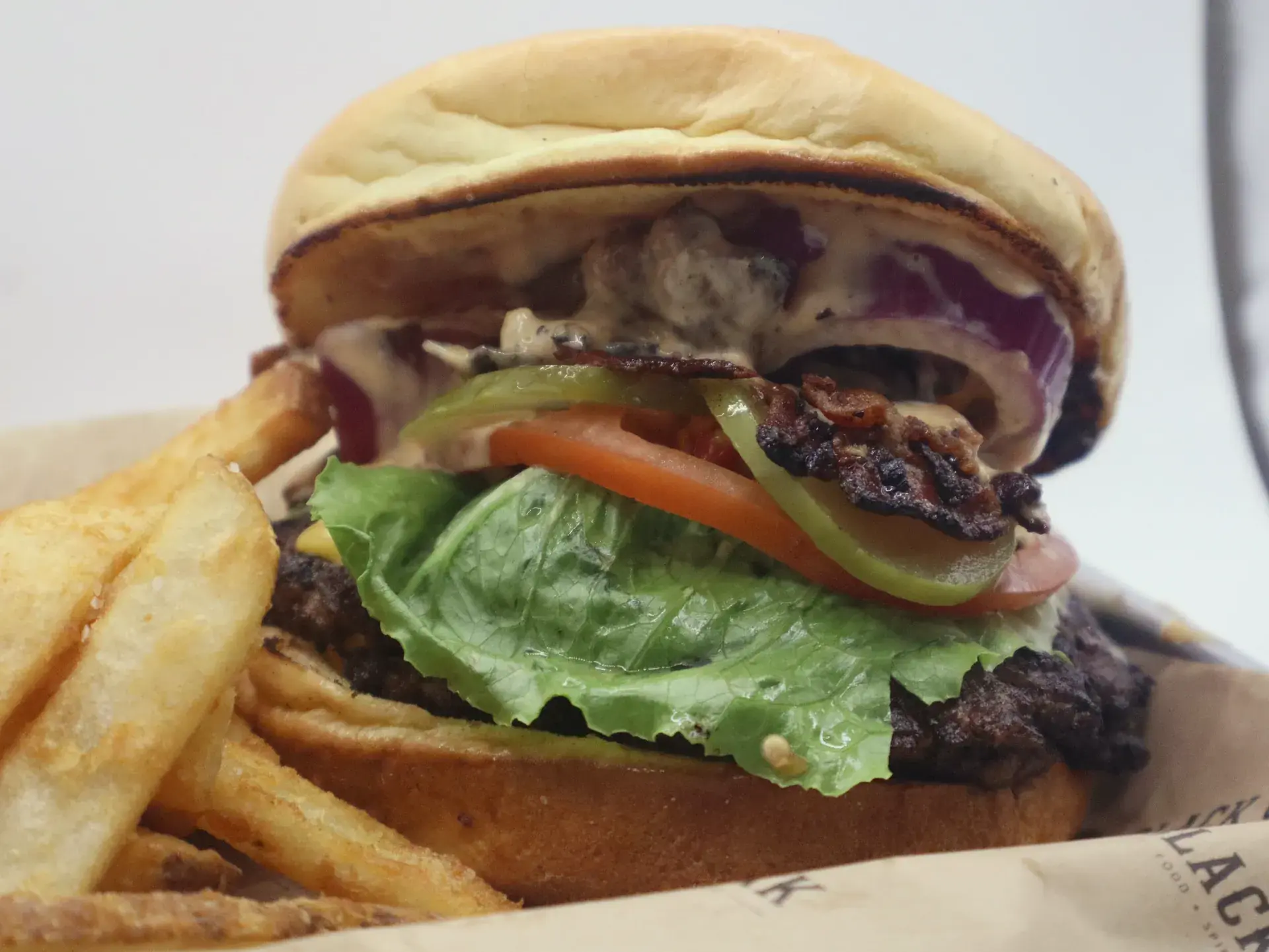 The Black Oak smashburger with cheese, bacon, lettuce, tomato, red onion, and pickle, served with fries.