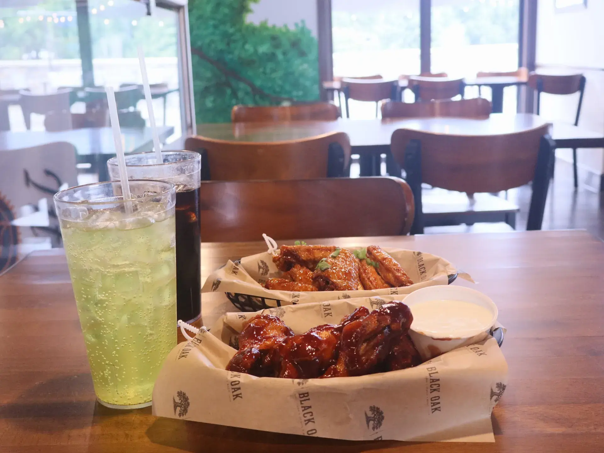 A table set with baskets of wings and cold drinks in the dining room at The Black Oak.